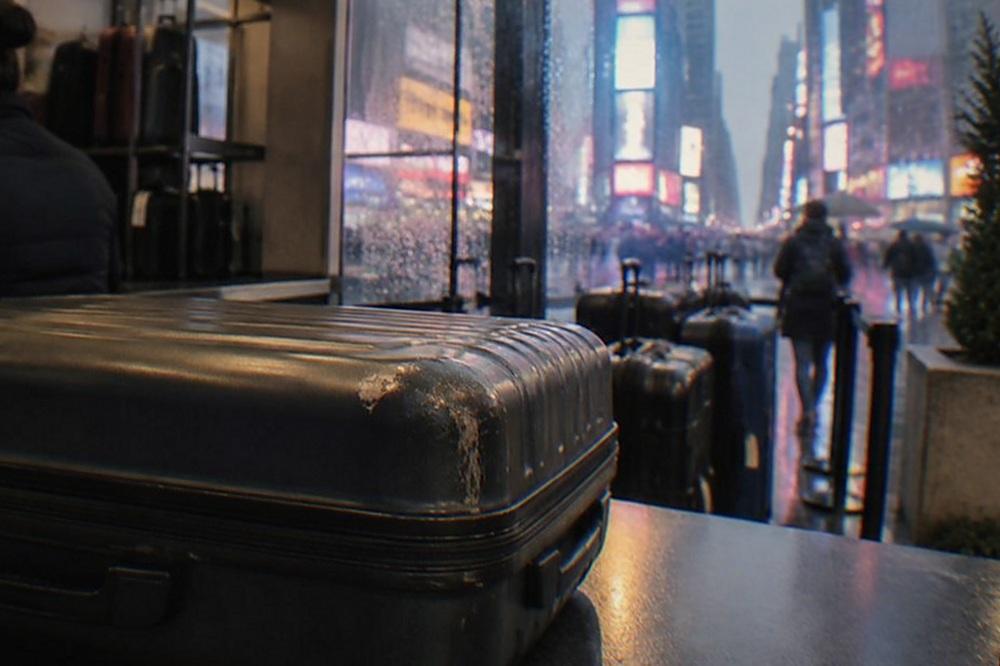 A staffed bag storage counter inside a New York shop, with suitcases lined up behind the counter