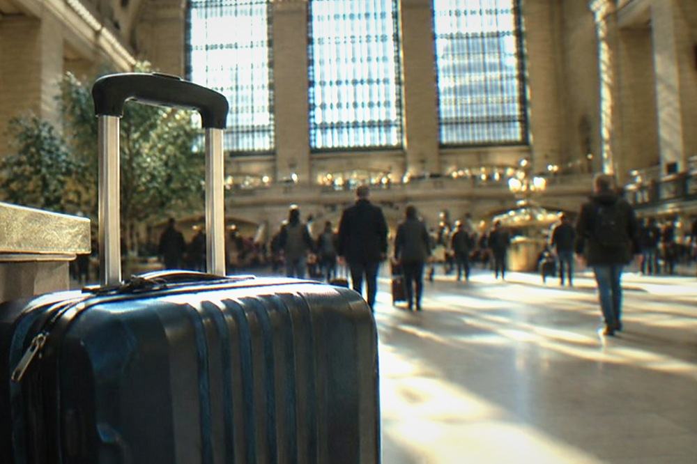 Train hall interior with a service desk and travellers with rolling suitcases