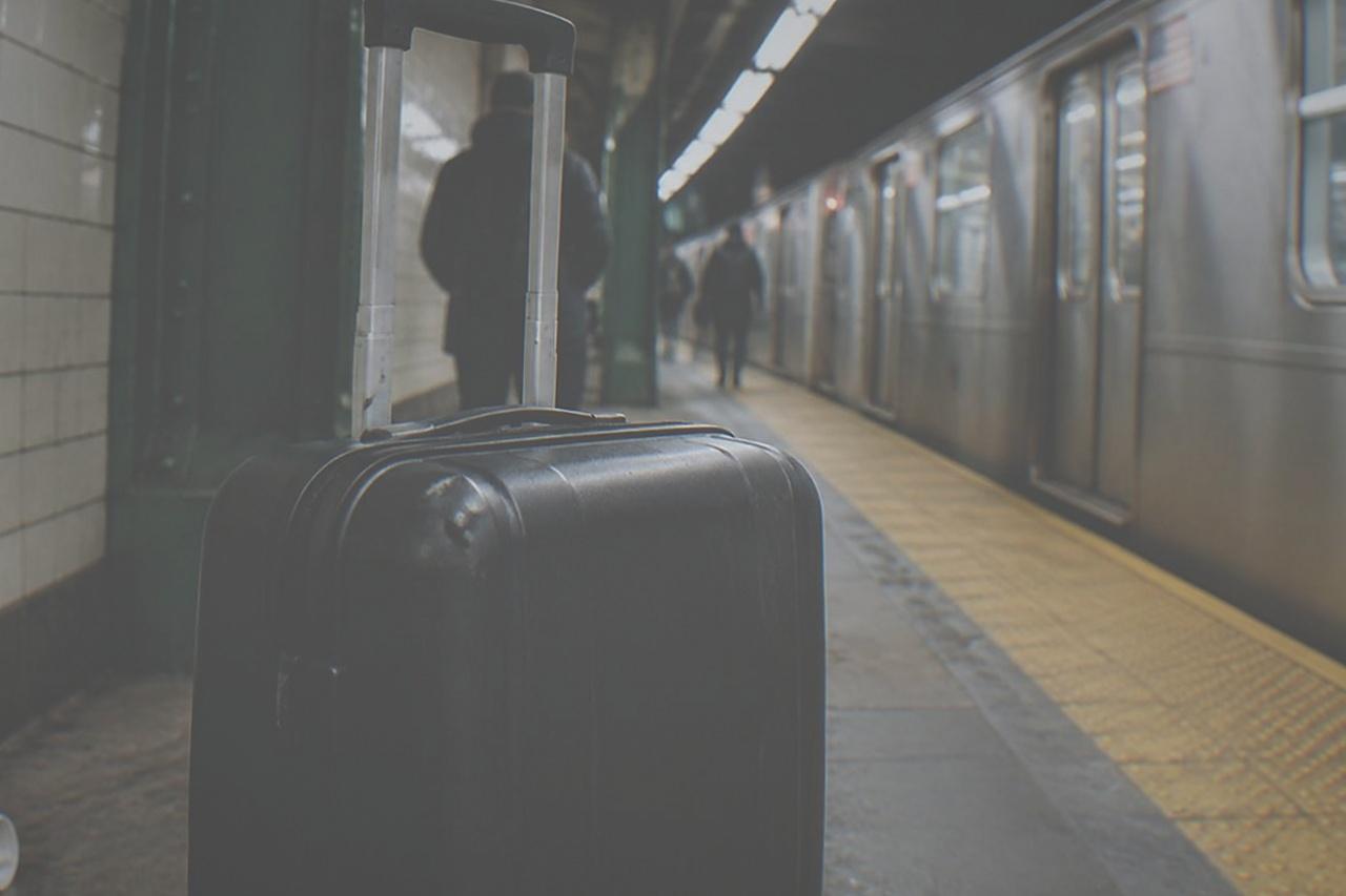 An empty New York subway platform with tiled columns and a stopped train at the platform edge