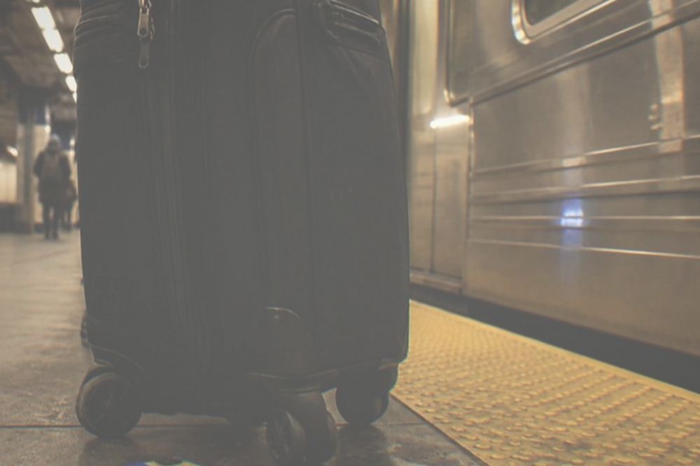 Late-night subway platform with a traveller holding a suitcase beside a train.
