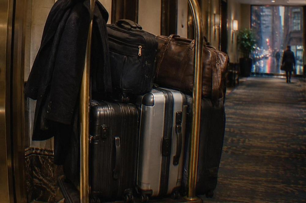 Bell cart loaded with suitcases parked in a hotel corridor beside a service door