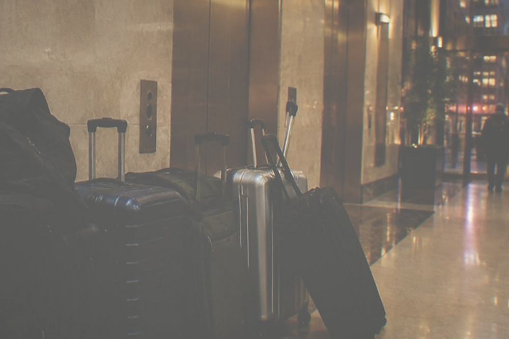 Suitcases lined up against the wall of a hotel lobby near the elevator bank