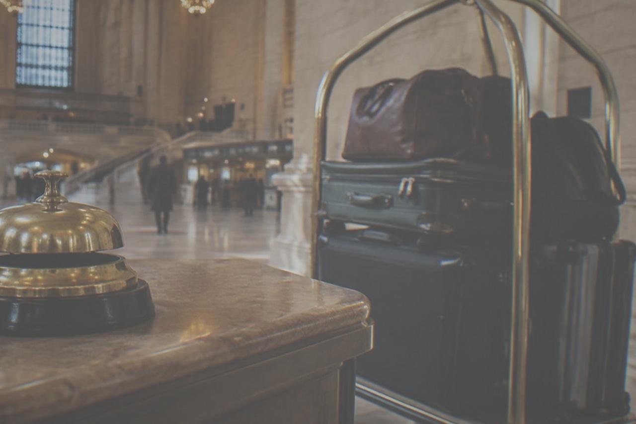 Hotel bell desk counter with brass bell and luggage cart in a lobby