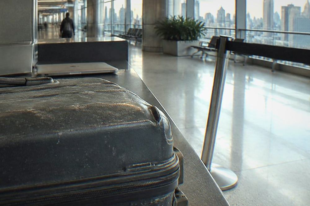 An empty airport service desk with a closed laptop and a queue barrier in a quiet terminal corridor.
