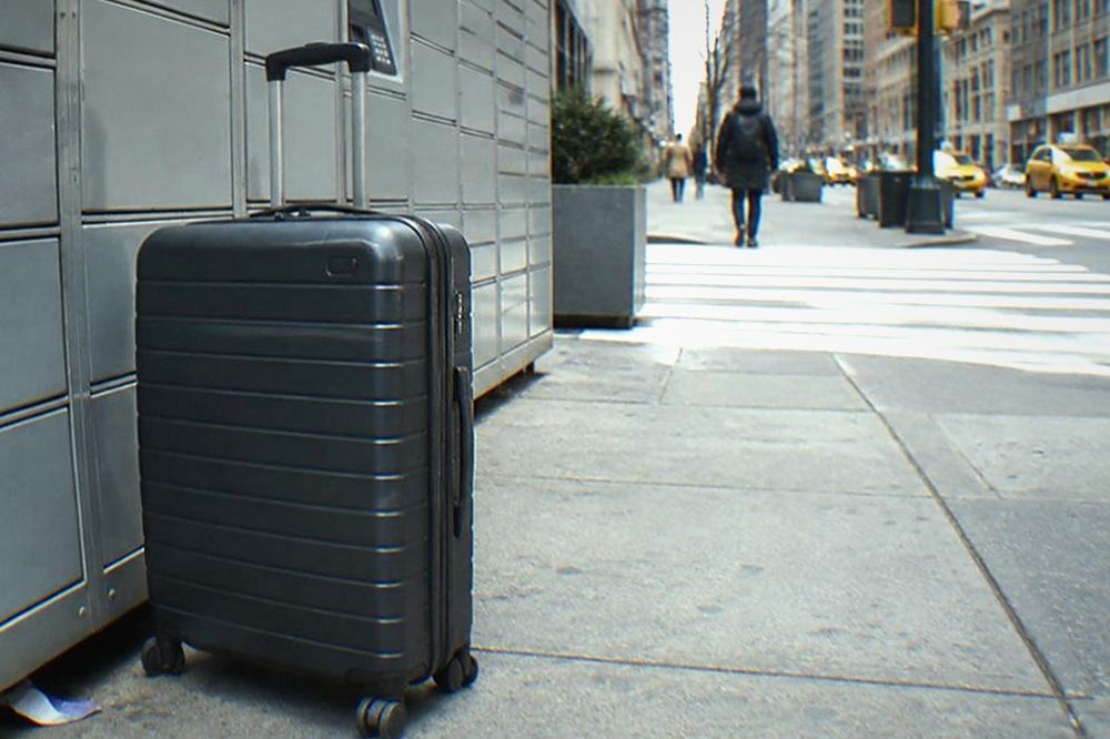 Row of grey metal parcel lockers mounted on a New York sidewalk beside a crosswalk