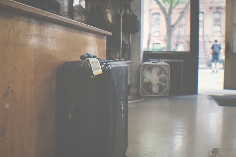 A tagged suitcase waiting on the floor behind a small business counter