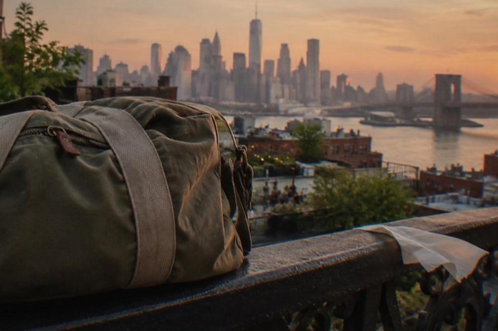 A closed suitcase standing beside a stone plaza railing with a skyline behind it