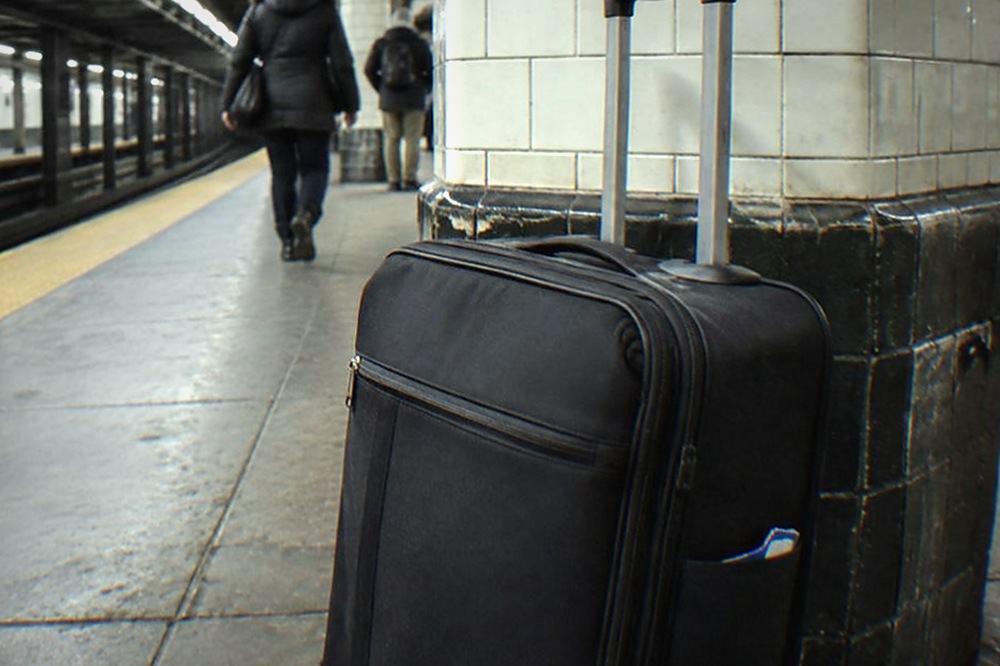 A subway platform with a closed suitcase resting near a column