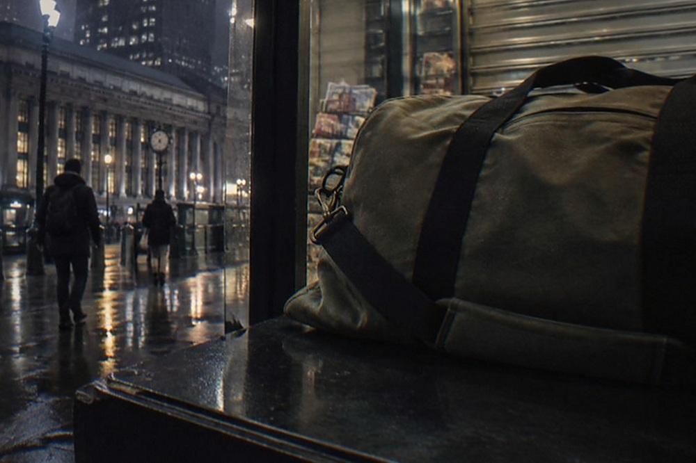 Dimly lit shopfront on a Manhattan side street at night with lights on inside and a shuttered newsstand beside it
