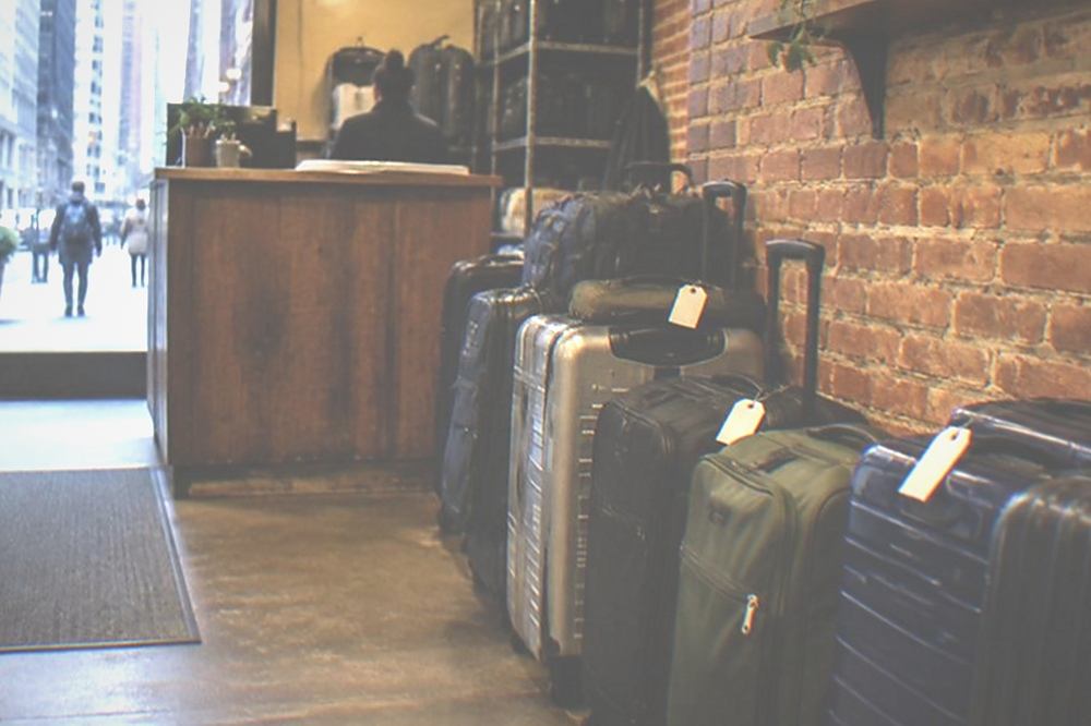 A shopfront storage point with a staffed counter and tagged suitcases lined along a wall