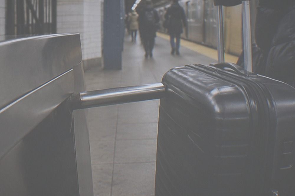 Suitcase resting beside a subway turnstile in a station