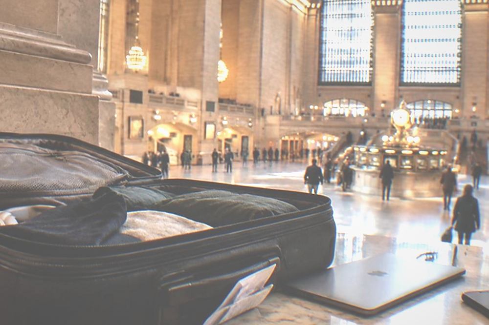Open suitcase on a counter with a laptop and phone set aside beside it