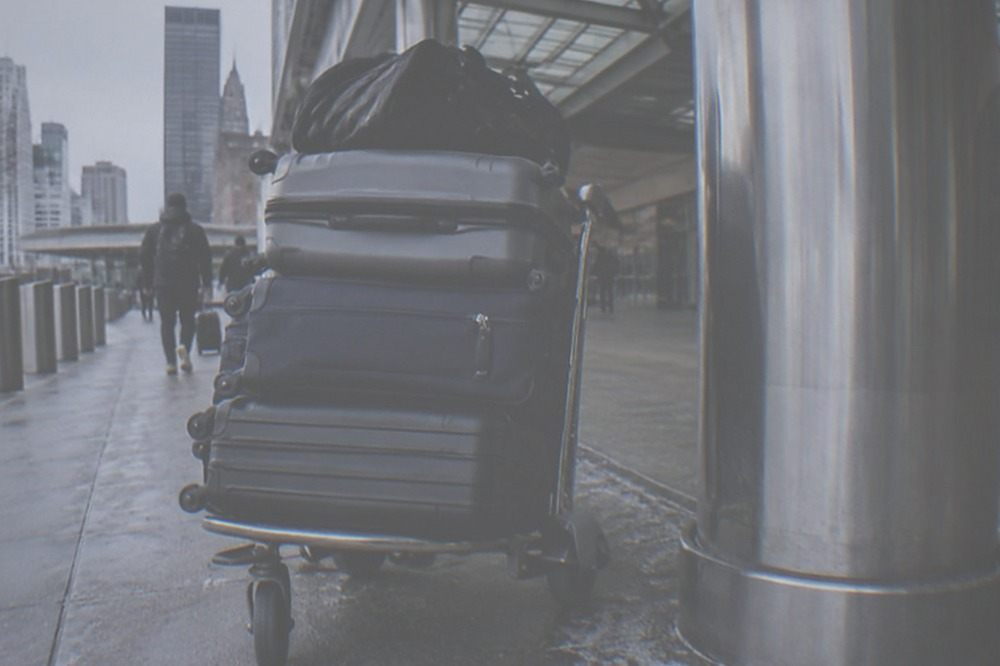 A luggage cart parked beside a terminal column near an airport entrance