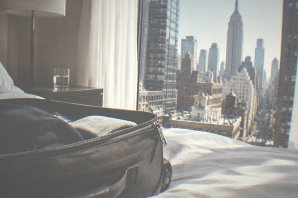 Empty made hotel bed in a bright room with morning light through the window