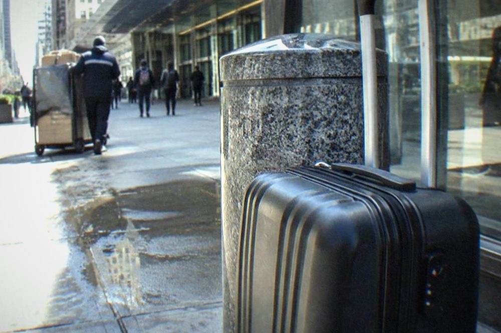 Sidewalk outside a station entrance with storefronts along the block