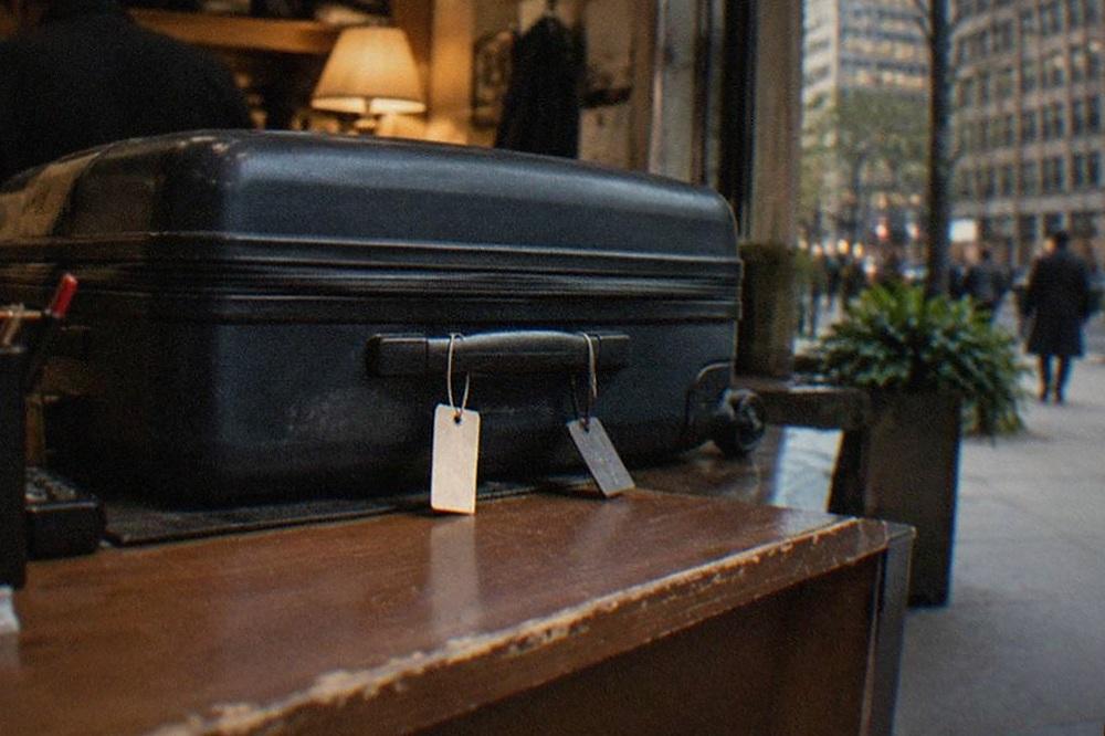 Suitcase waiting behind the counter of a small shop with a staffed desk