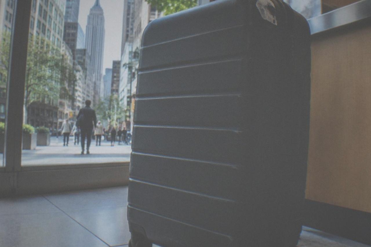 A closed suitcase standing beside a shop counter in a bright New York storefront