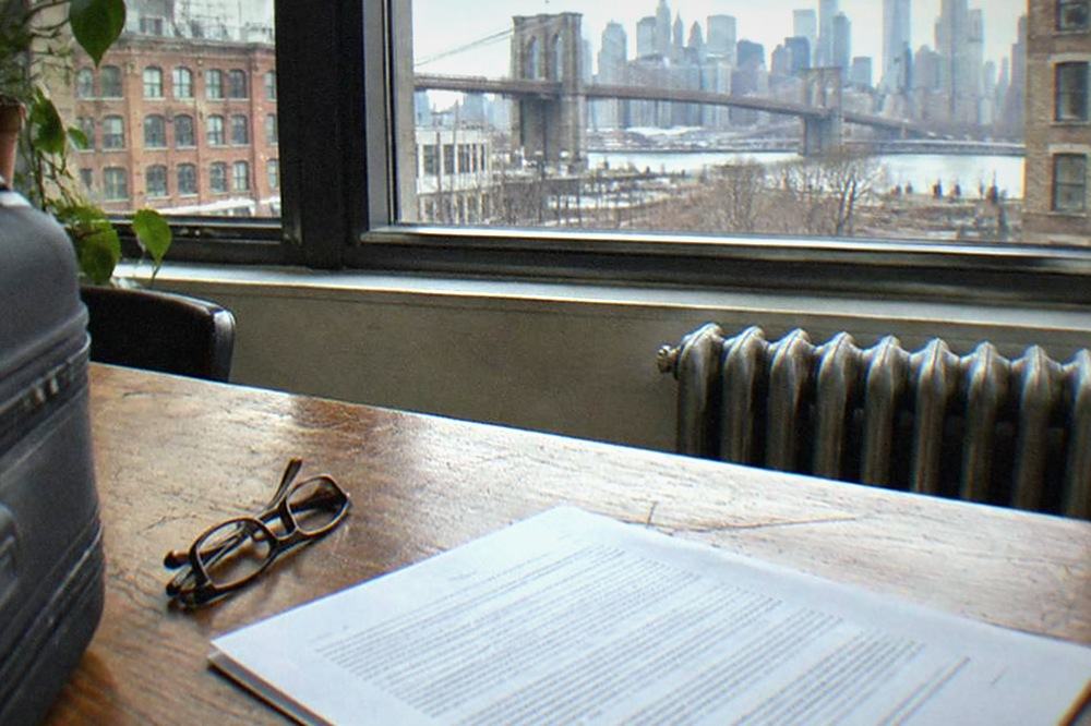 A printed contract document on a wooden desk beside a pair of glasses