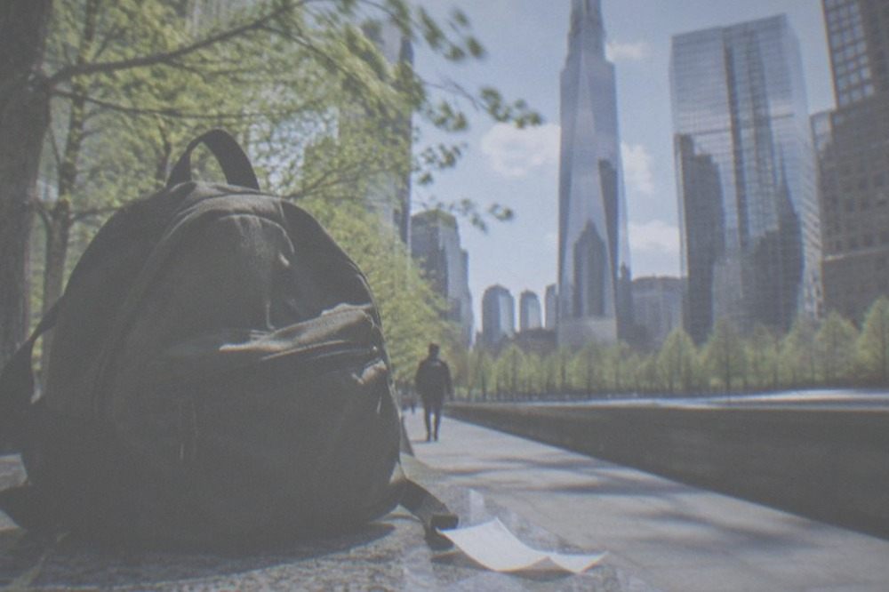 A traveller walking a New York sidewalk holding a small day bag