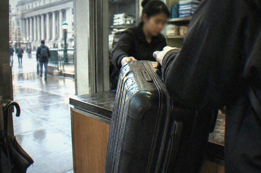 A staffed counter in a small shop with a suitcase being handed across the counter
